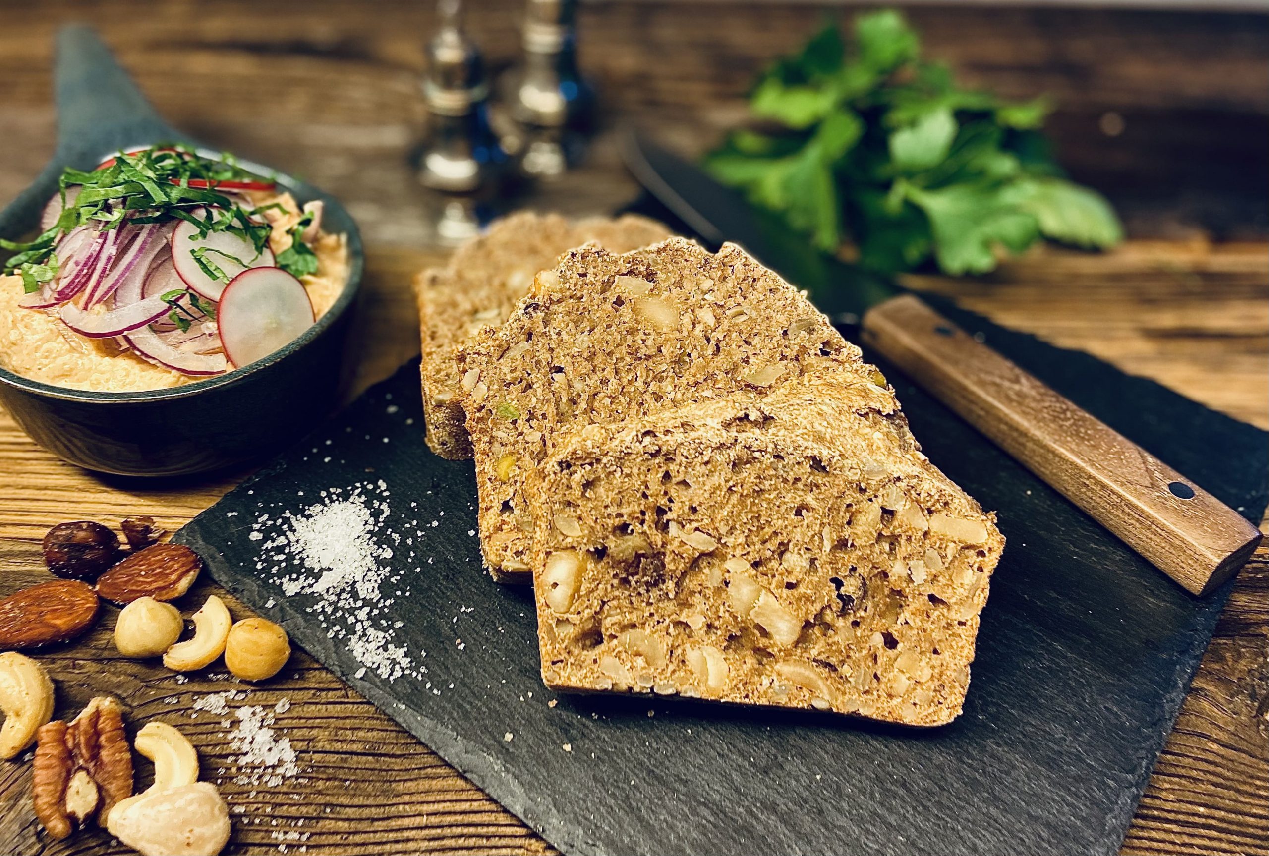 Nussbrot mit Spundekäse mit Nüssen und Messer auf Schneidebrett 