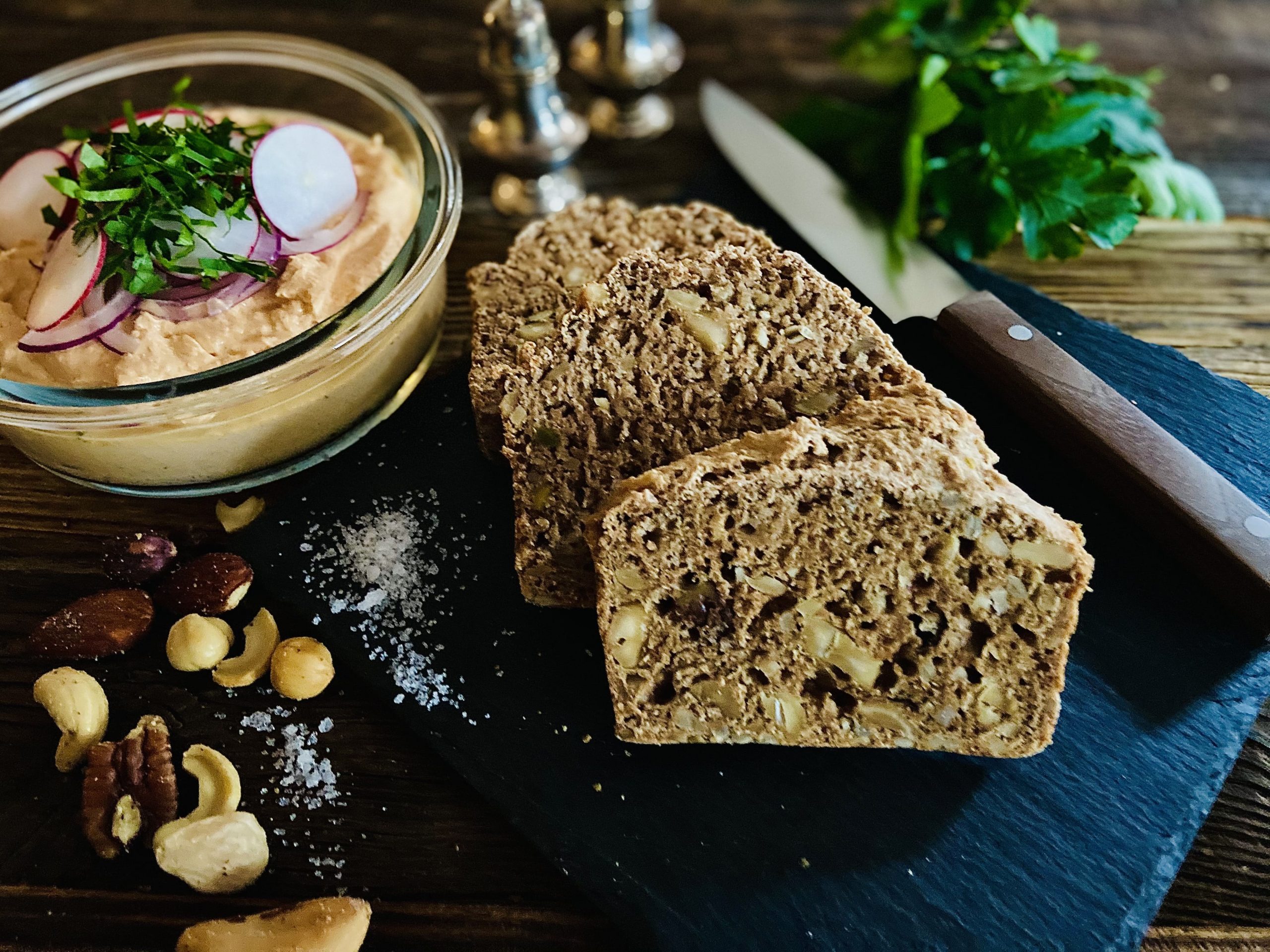 Nussbrot mit Spundekäse und Nüssen auf Schneidebrett