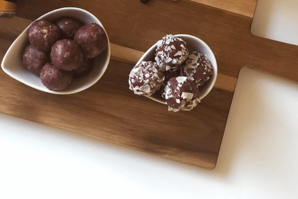 selbstgemachte Pink Energy Balls in Schälchen auf Brett