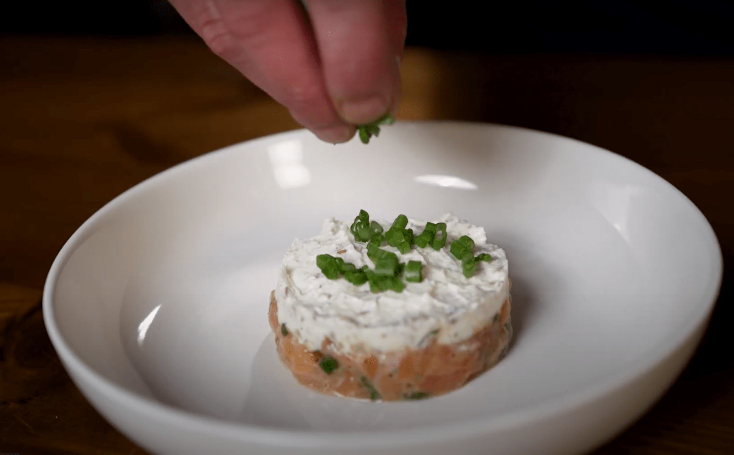 Lachstartar mit Frischkäse mit Kräutern garnieren