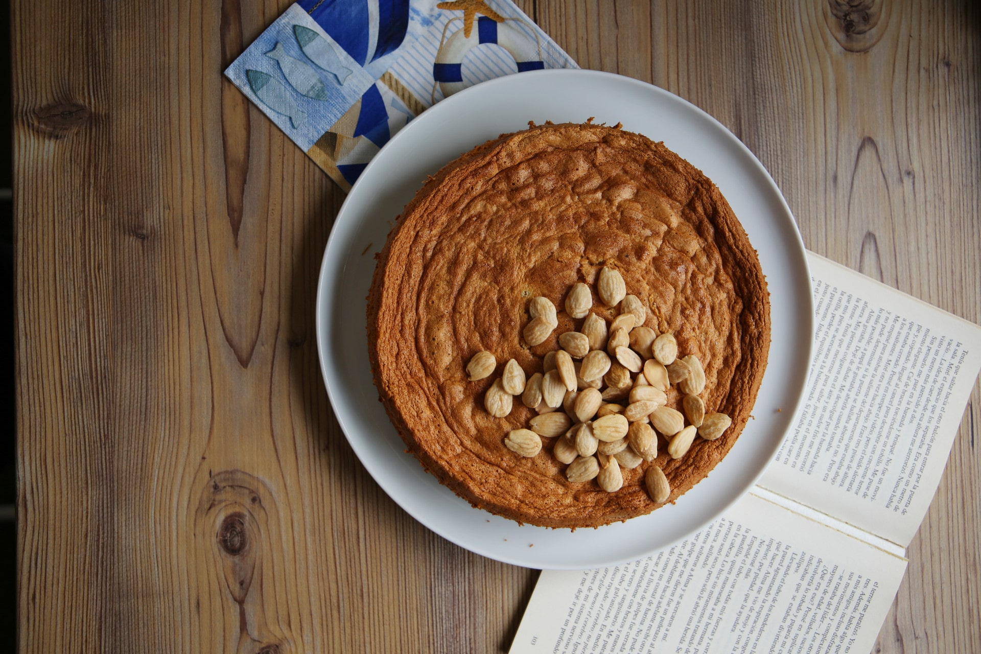 Mallorquinischer Mandelkuchen auf Teller neben Buch